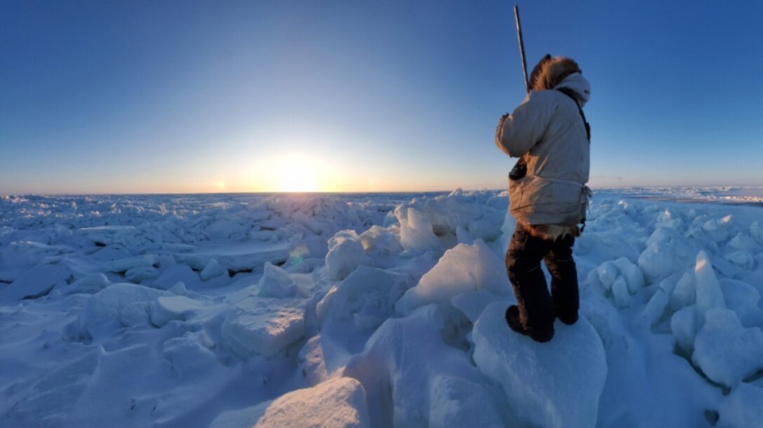 Hombre observando el horizonte del océano Ártico congelado en Point Hope, Alaska, ilustrando los límites físicos de la región.