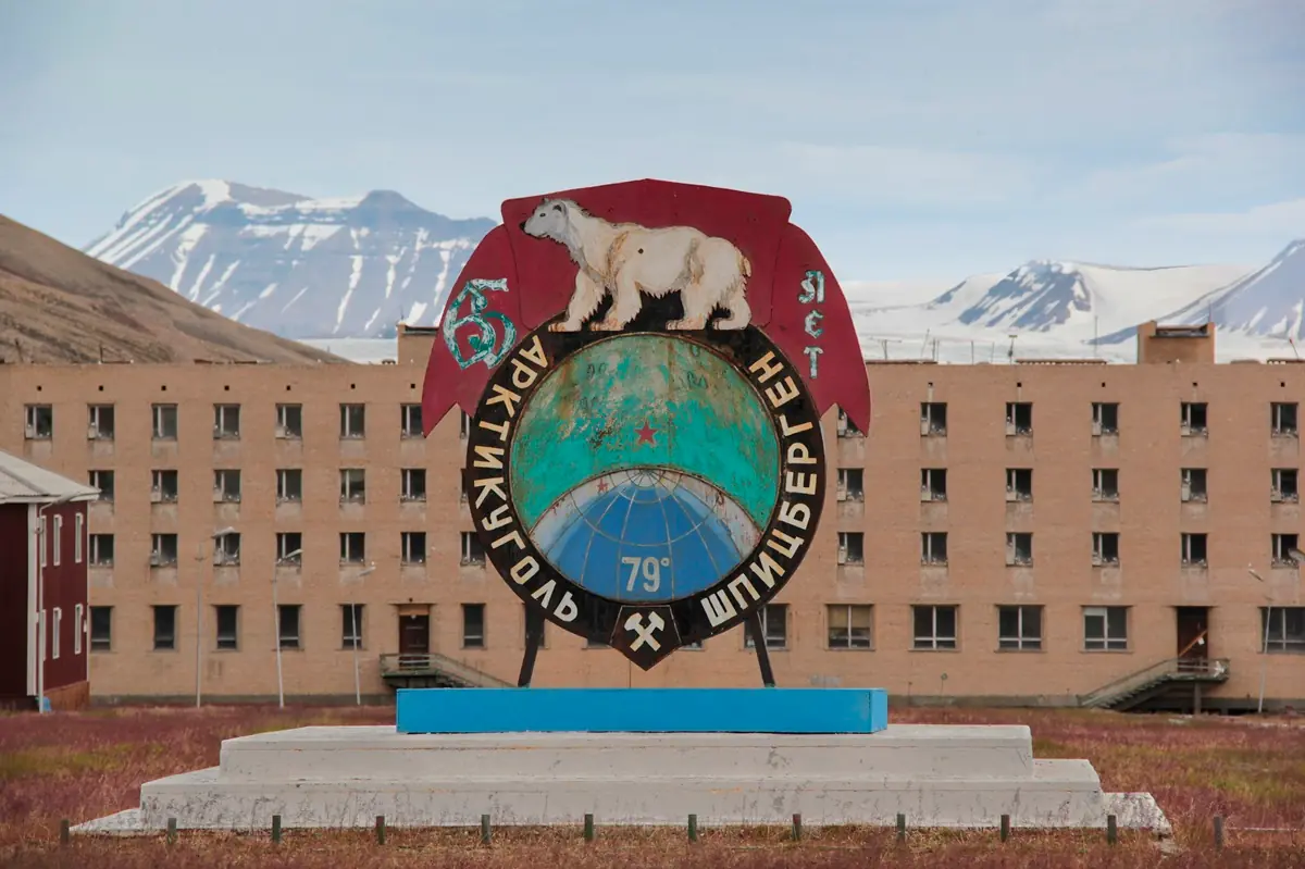 Vista panorámica de Pyramiden, el asentamiento minero soviético abandonado en Svalbard, Noruega, con el fiordo y las montañas árticas al fondo.