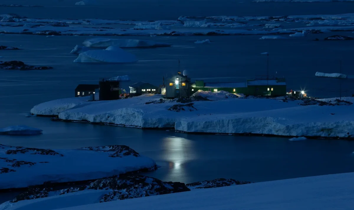 La Base de Investigación Akademik Vernadsky iluminada durante la noche polar antártica, rodeada de hielo marino en la Isla Galindez, Antártida.