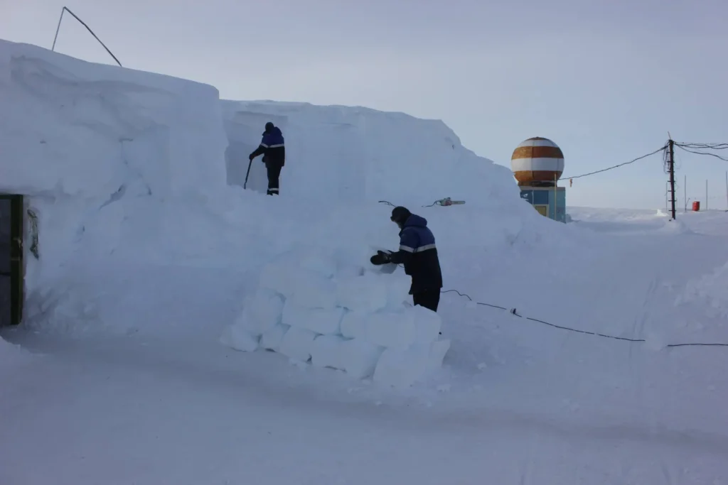 Trabajadores cortan bloques de hielo para obtener agua en la estación rusa Vostok, en el interior de la Antártida, bajo un cielo despejado y nieve compacta.