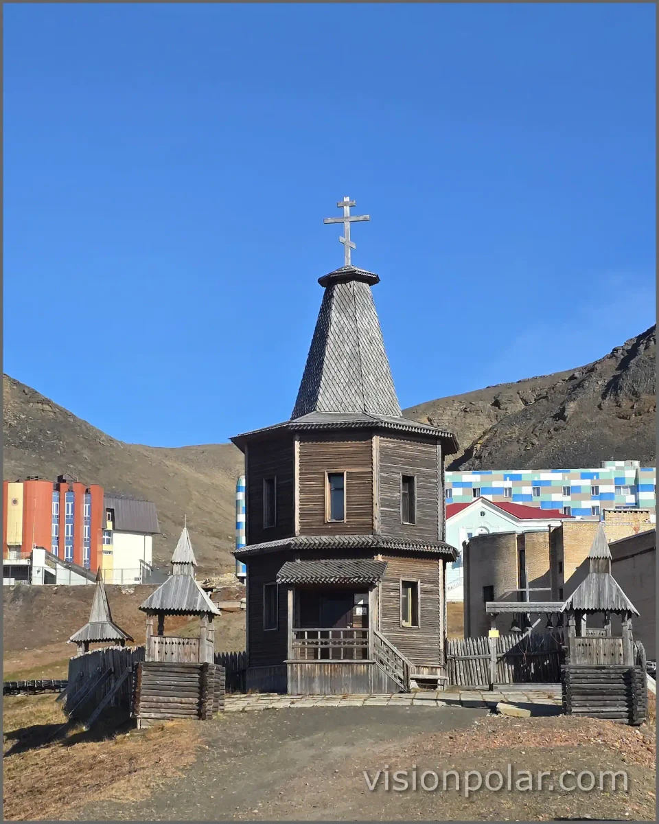 Iglesia ortodoxa de madera en Barentsburg, Svalbard, con viviendas y montañas al fondo