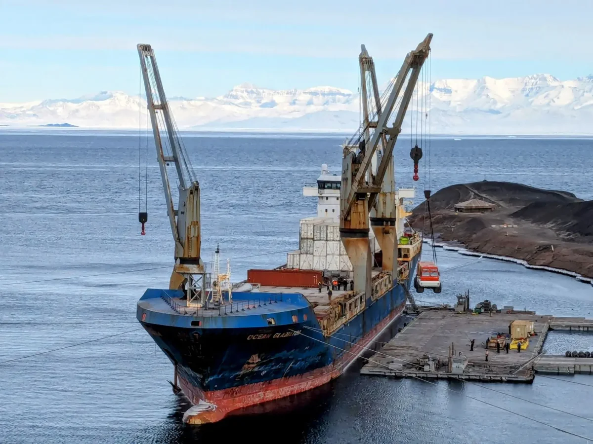 El buque de carga Ocean Gladiator amarrado en Winter Quarters Bay iza con su grúa el vehículo polar Ivan the Terra Bus en la estación McMurdo.