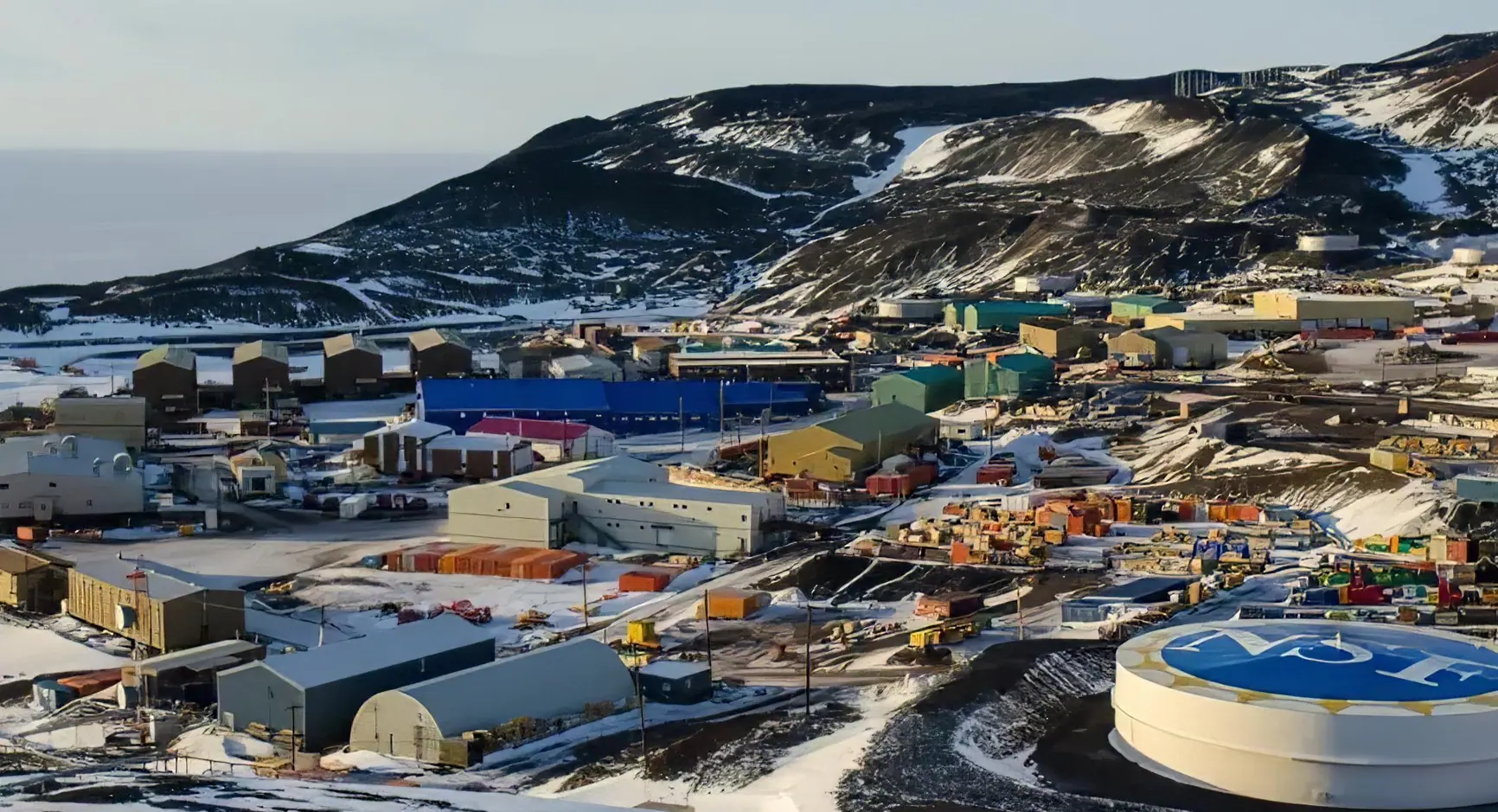 Vista panorámica de los edificios, almacenes y tanques de combustible de la estación McMurdo sobre el terreno volcánico de la isla Ross.