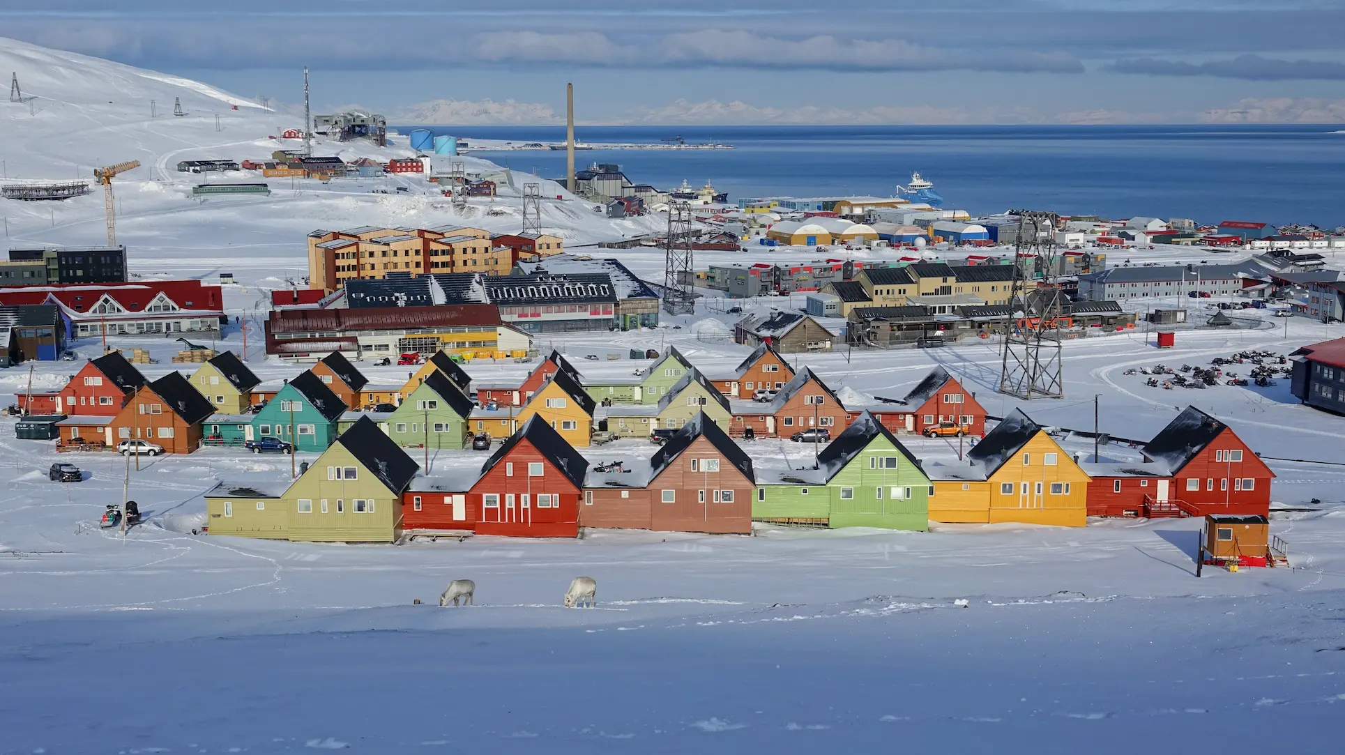 Casas de colores en la nieve de Longyearbyen, Svalbard, con montañas nevadas al fondo.